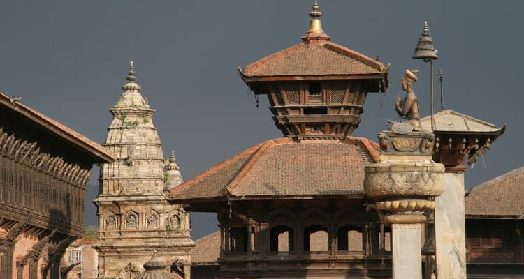 Oude pagodastijl tempels met sierlijke daken die zich aftekenen tegen een dramatische donkere lucht in Bhaktapur.