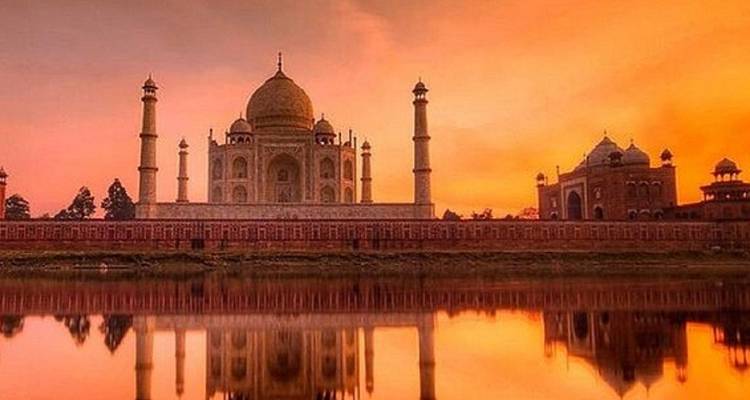 Majestueus uitzicht op de Taj Mahal die weerkaatst in een rustige rivier bij zonsondergang.