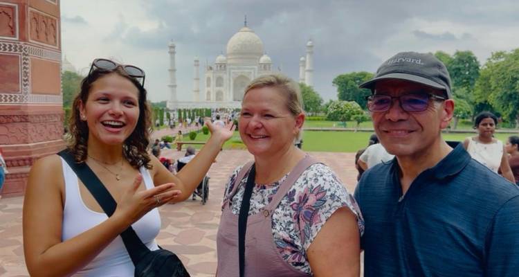 Trois touristes enthousiastes posent avec le Taj Mahal qui s'élève derrière eux par une journée nuageuse.