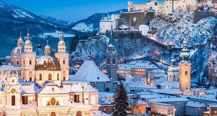 El horizonte barroco nevado de Salzburgo resplandece bajo un crepúsculo vespertino de azul nítido.