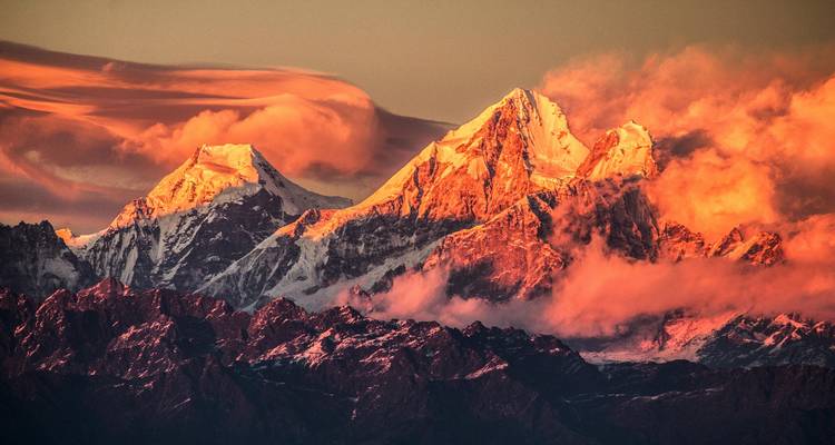 Zonsondergang die weerkaatst tegen besneeuwde bergtoppen