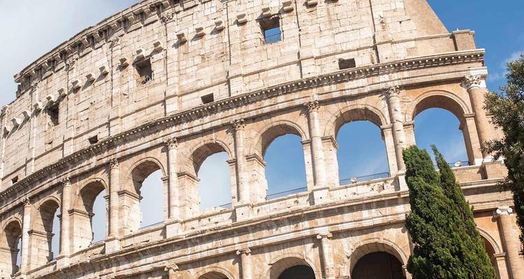 Détail des arches de pierre antiques du Colisée de Rome se détachant sur un ciel bleu doux.
