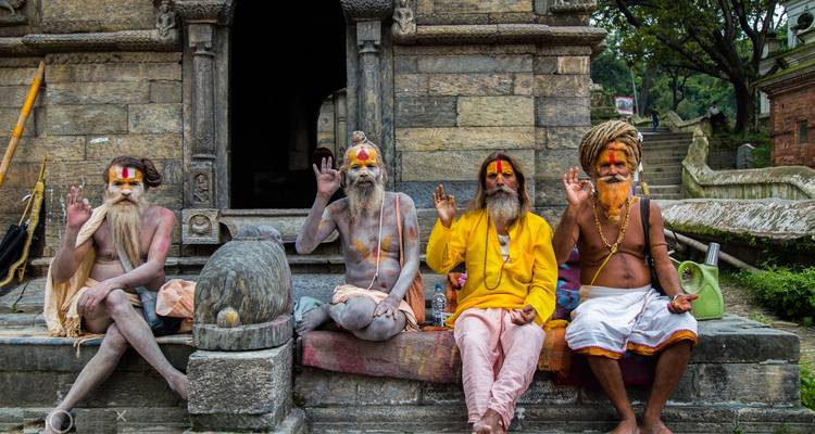 Four holy men sitting outside a temple posing for the camera.