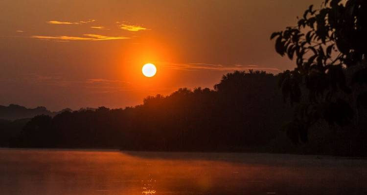 Amanecer sobre un río con niebla al fondo.