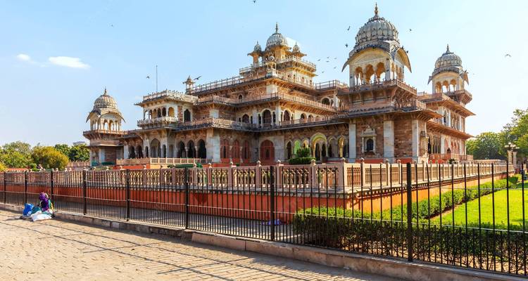 Las cúpulas ornamentadas y los balcones del Museo Albert Hall se alzan detrás de una valla de hierro forjado en un día brillante.