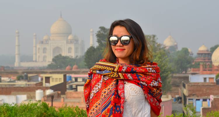 Persoon die glimlacht met de Taj Mahal op de achtergrond.