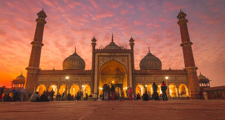 Jama Masjid tegen een prachtige zonsonderganghemel met mensen.