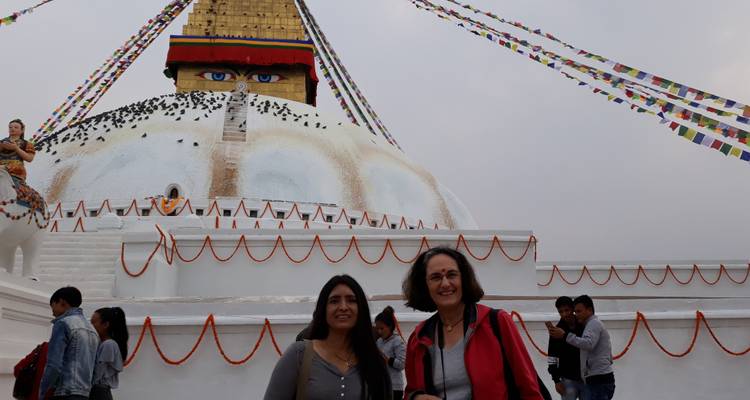 Bezoekers die poseren voor de pas gerenoveerde Boudhanath Stupa versierd met goudsbloem slingers