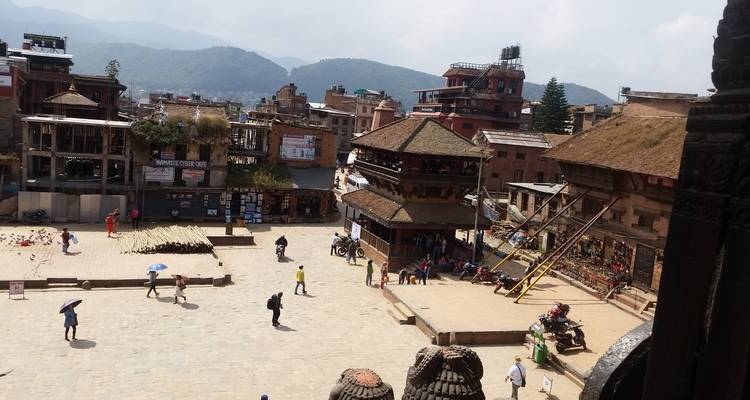 View over Bhaktapur square with traditional buildings, scattered visitors and surrounding hills