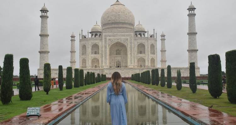 Femme devant le Taj Mahal avec un reflet dans l'eau.