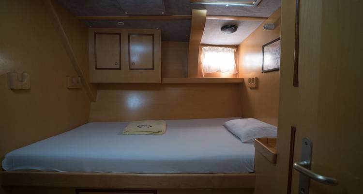 Yacht cabin with a bed and wooden walls.