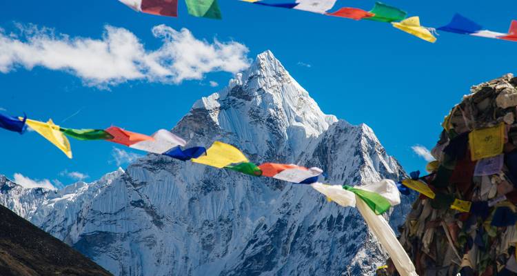 Montagne enneigée avec des drapeaux de prière colorés au premier plan.