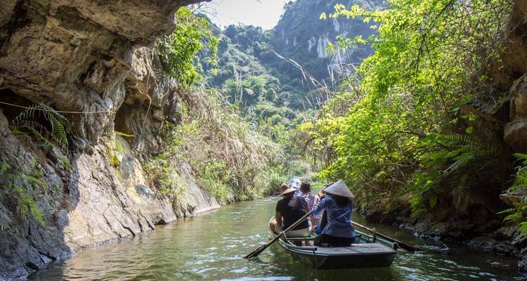 Personas en un bote navegando por un río estrecho con vegetación exuberante en ambos lados.