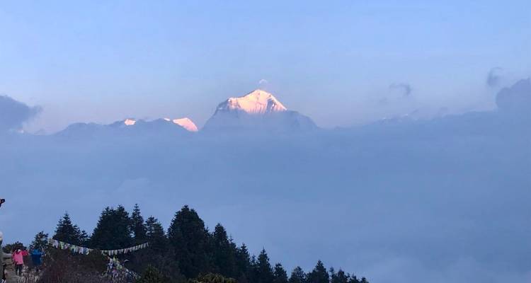 Sommet de montagne illuminé par la lumière du soleil au-dessus des nuages.