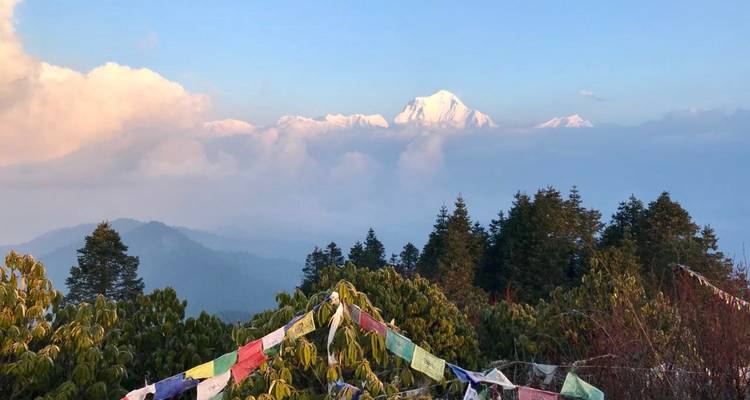 Montagnes avec des sommets enneigés et des drapeaux de prière au premier plan.