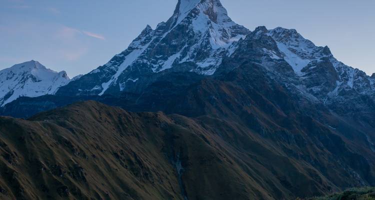 Machapuchare mountain view rising above grassy hills.