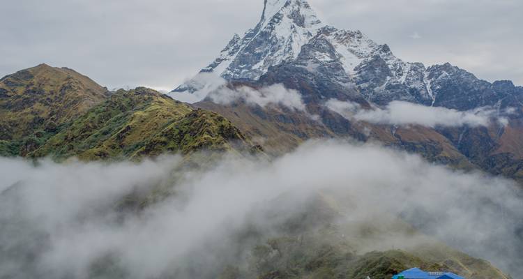 Machapuchare mountain behind mist-covered hills.