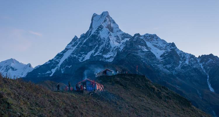 Campers at the base of Machapuchare mountain at dusk.