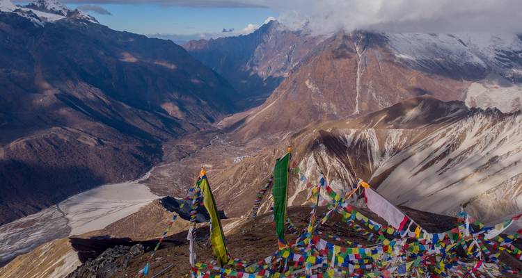 Drapeaux de prière colorés surplombant une vaste vallée de montagne.