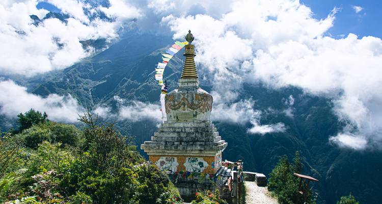 Estupa con banderas de oración coloridas en un paisaje montañoso.