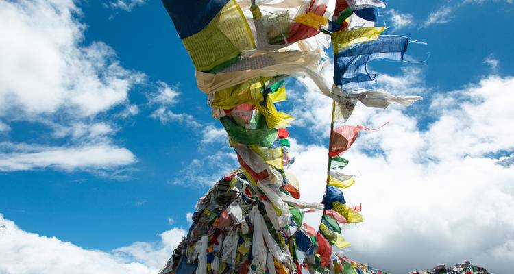 Colorful prayer flags blowing in the wind against a blue sky.