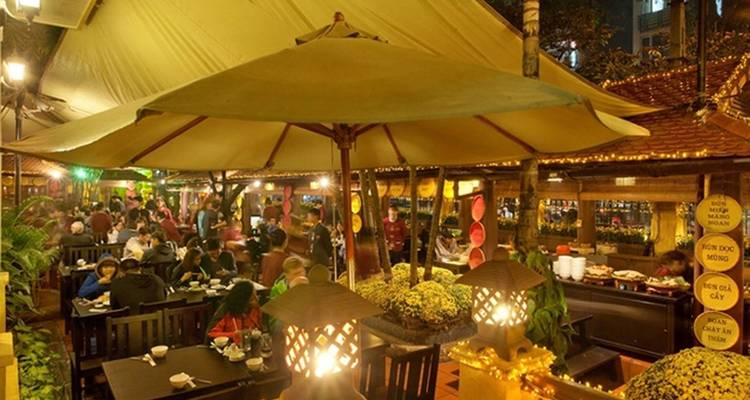 Buiteneetgelegenheid met levendige verlichting en mensen die dineren.