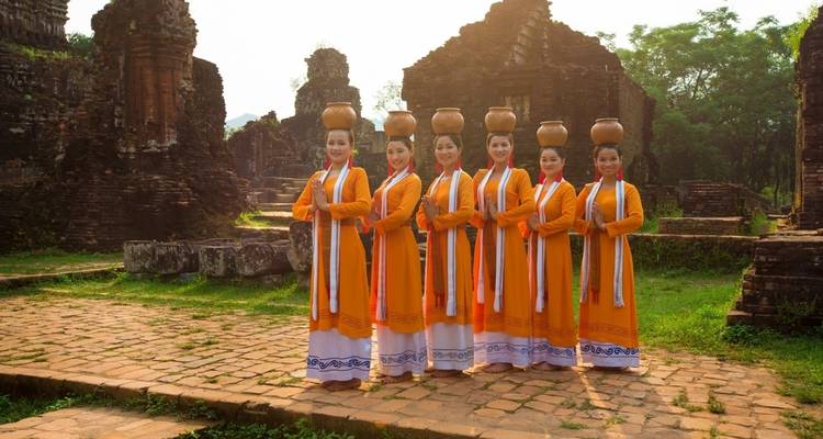 Groep vrouwen in traditionele kledij staand op een oude ruïnelocatie.