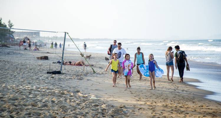 Kinderen en volwassenen op een zandig strand aan zee.