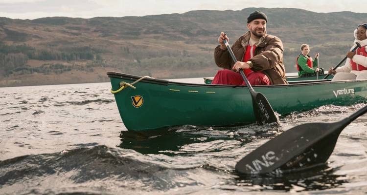 Les canoéistes pagaient sur un loch écossais balayé par les vents avec des collines ondoyantes au-delà.