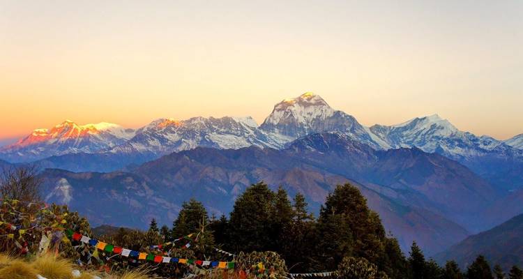 Bergketen tijdens zonsondergang met gebedsvlaggen op de voorgrond.