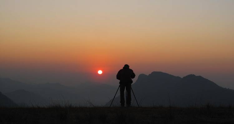 Fotograaf die een zonsondergang boven bergketens vastlegt.