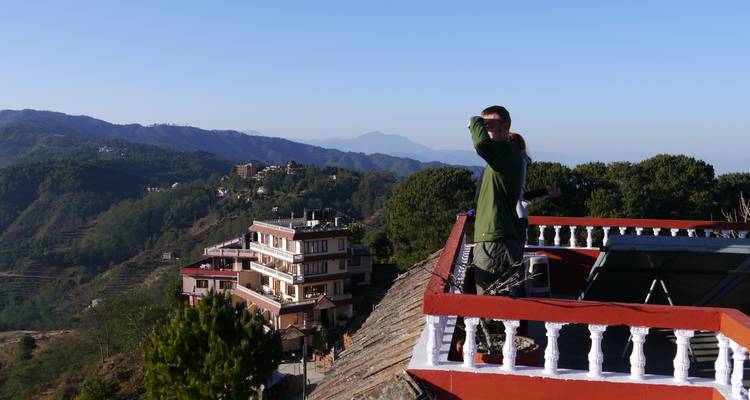 Person looking over a balcony with hills in the background.