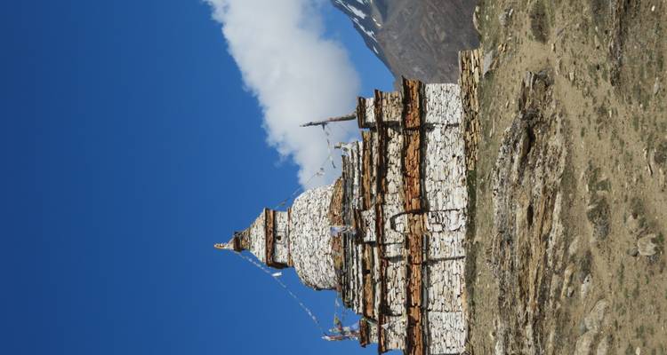 Een stenen bouwwerk tegen een blauwe lucht en bergen.