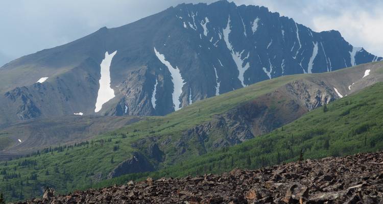 Impressive mountain range with snow patches and lush green slopes.