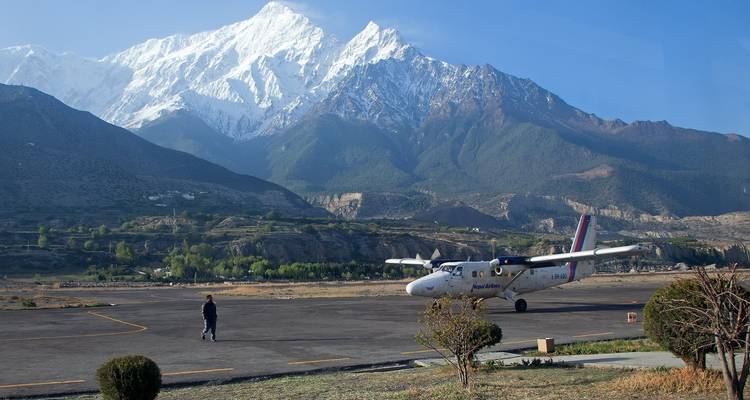 Petit avion sur le tarmac avec des montagnes en arrière-plan.