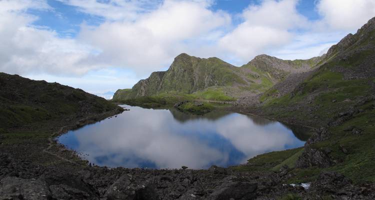 Reflective lake with mountains and clouds mirrored on the surface.
