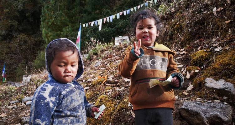 Zwei Kinder spielen draußen in einer natürlichen Umgebung.
