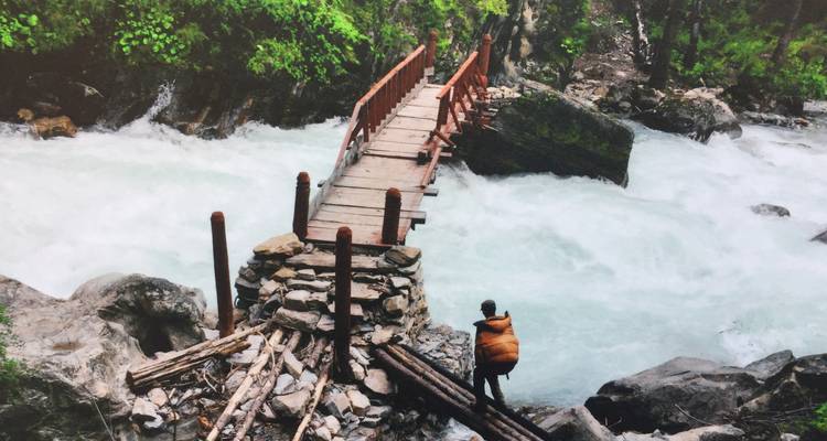 Person crossing a wooden bridge over a river.