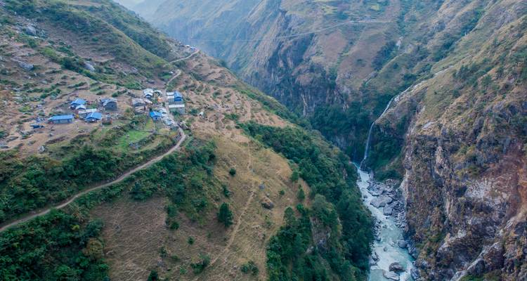 Aerial view of a village in a deep, lush valley with a winding river.