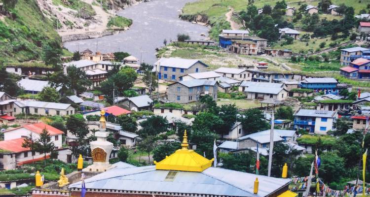 Colorful village by a river in a hilly landscape.