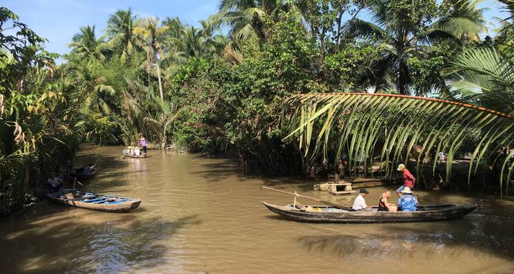Fluss mit Booten, umgeben von tropischen Bäumen.