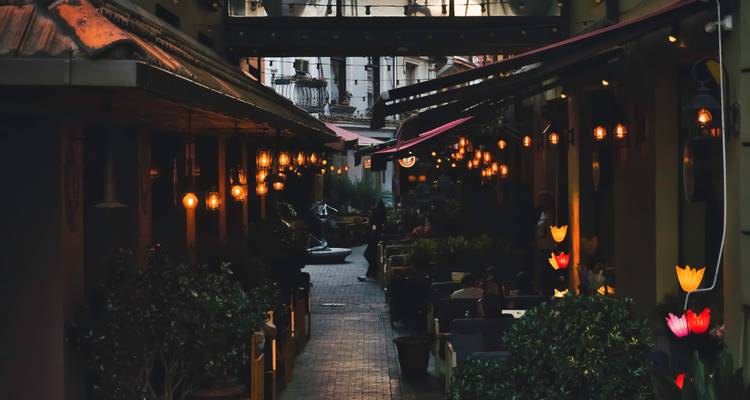 Narrow alleyway with hanging lights and outdoor seating.