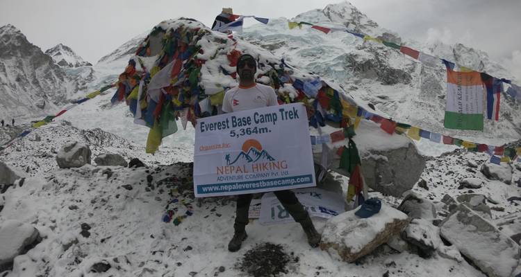 Person holding a sign with Everest Base Camp in the snow.
