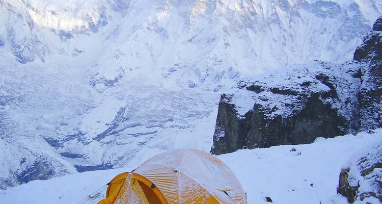 Une tente recouverte de neige dans un cadre montagneux.