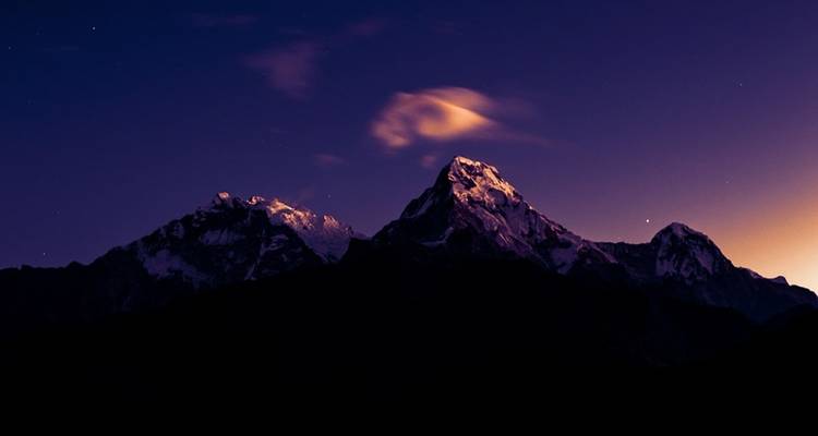 Sommets de montagnes enneigés sous un ciel nocturne.