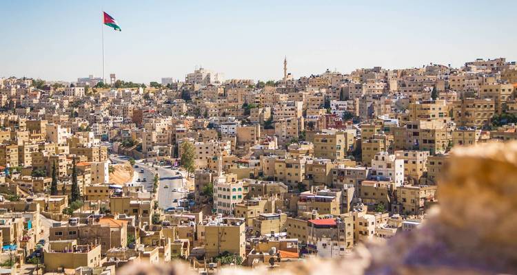 Stadtansicht mit zahlreichen sandfarbenen Gebäuden und einer großen Flagge.
