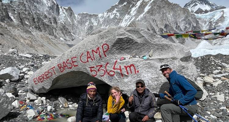 Les trekkers célèbrent à côté du rocher du Camp de base de l'Everest marqué 5364 m avec d'imposants sommets en arrière-plan.