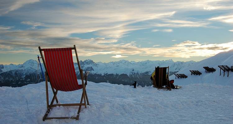 Besneeuwde berglandschap met een stoel en heldere hemel.