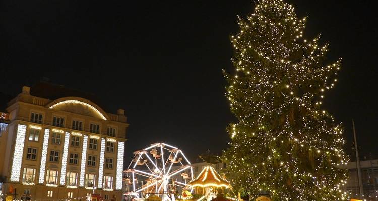 Kerstmarkt 's nachts met een grote kerstboom en reuzenrad.