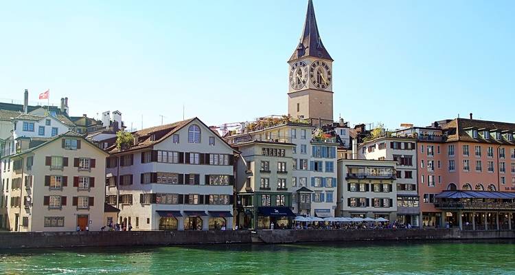 Rivière bordée de vieux bâtiments et d'une tour d'horloge.